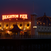 alt="glowing neon lights of Brighton Pier lighting up the seafront"