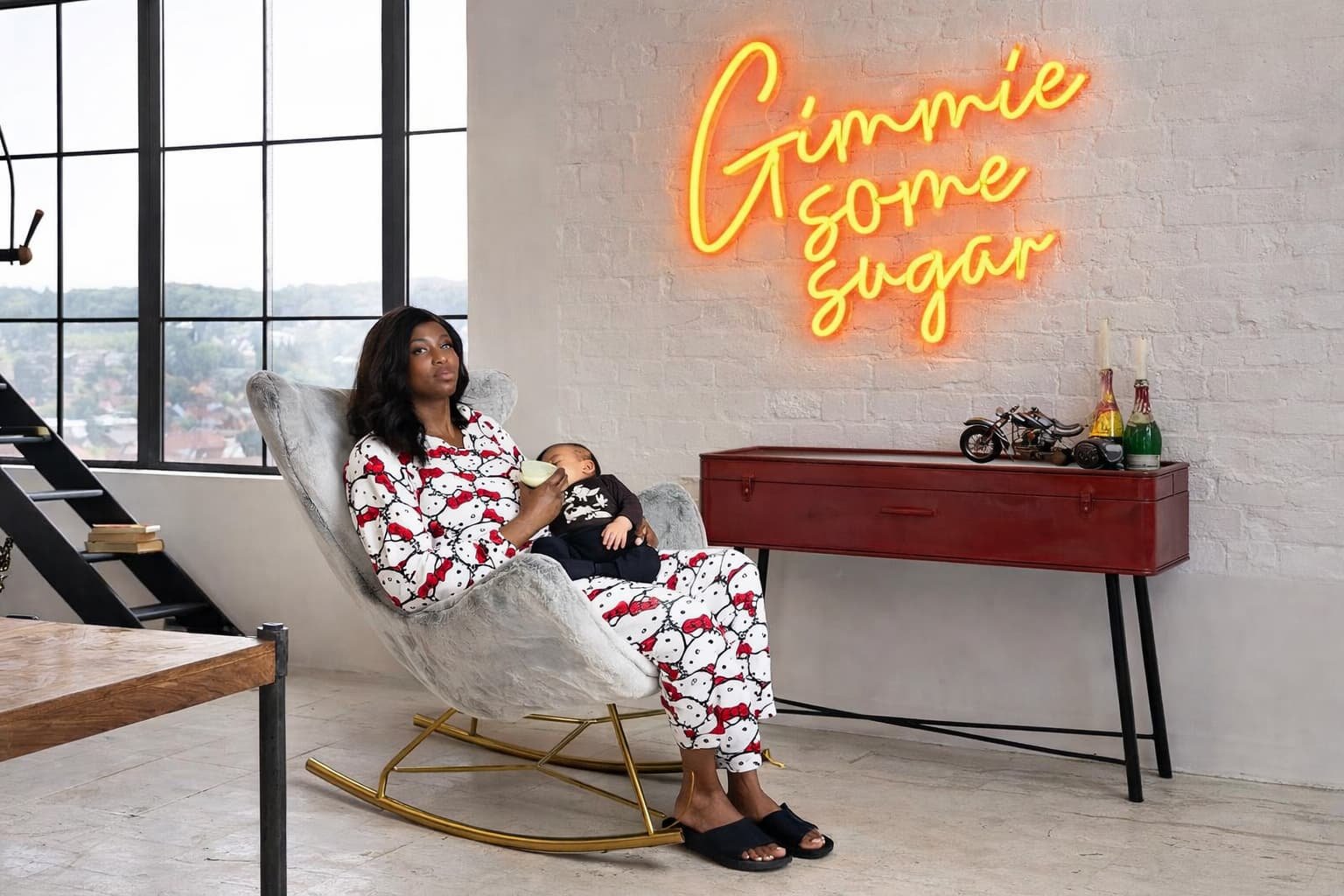 alt="A mother comfortably breastfeeding in a grey nursery chair"