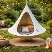 Cacoon hanging chair suspended from tree in backyard